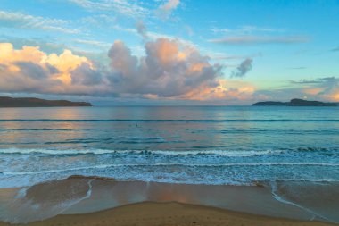 Central Coast, NSW, Avustralya 'daki Umina Sahili' nde küçük dalgalar ve yağmur bulutlarıyla gün batımı deniz manzarası..