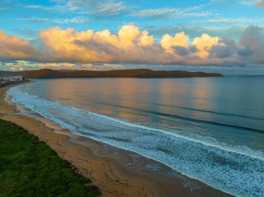 Central Coast, NSW, Avustralya 'daki Umina Sahili' nde küçük dalgalar ve yağmur bulutlarıyla gün batımı deniz manzarası..