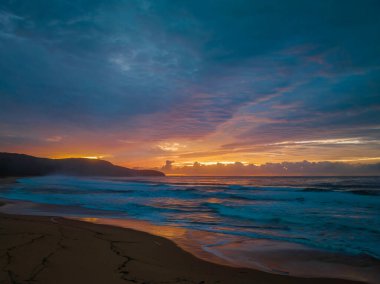 Sunrise seascape with colourful cloud covered sky at Killcare Beach on the Central Coast, NSW, Australia.
