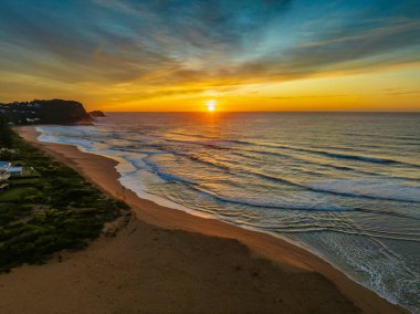 Avoca Lagoon ve Avoca Sahili 'ndeki NSW, Avustralya' daki Avoca Sahili 'nde bulutlu ve yumuşak denizli hava gündoğumu.