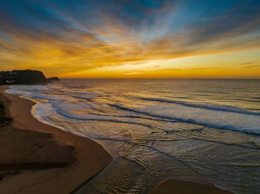 Avoca Lagoon ve Avoca Sahili 'ndeki NSW, Avustralya' daki Avoca Sahili 'nde bulutlu ve yumuşak denizli hava gündoğumu.