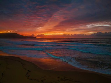 Sunrise seascape with colourful cloud covered sky at Killcare Beach on the Central Coast, NSW, Australia.