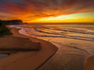Avoca Lagoon ve Avoca Sahili 'ndeki NSW, Avustralya' daki Avoca Sahili 'nde bulutlu ve yumuşak denizli hava gündoğumu.