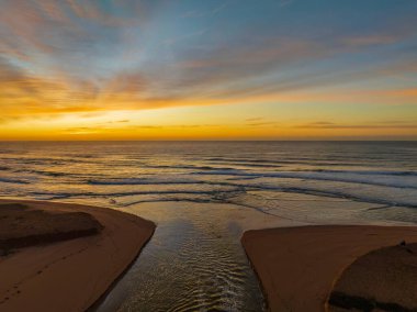 Avoca Lagoon ve Avoca Sahili 'ndeki NSW, Avustralya' daki Avoca Sahili 'nde bulutlu ve yumuşak denizli hava gündoğumu.