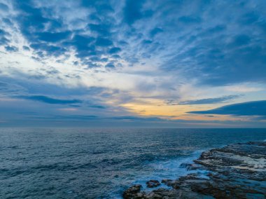 Sunrise seascape with high cloud, rocks and small waves at Avoca Beach on the Central Coast, NSW, Australia.