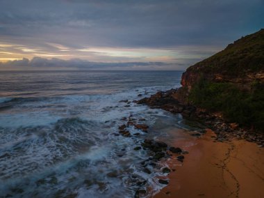 Sunrise seascape with colourful cloud covered sky at Killcare Beach on the Central Coast, NSW, Australia.