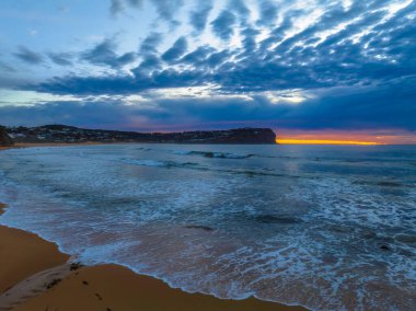 Aerial sunrise with medium and high cloud filled sky with small waves at  Macmasters Beach on the Central Coast, NSW, Australia.