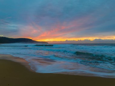 Sunrise seascape with colourful cloud covered sky at Killcare Beach on the Central Coast, NSW, Australia.