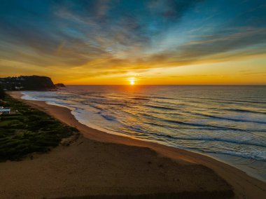 Avoca Lagoon ve Avoca Sahili 'ndeki NSW, Avustralya' daki Avoca Sahili 'nde bulutlu ve yumuşak denizli hava gündoğumu.