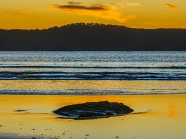 Sunrise seascape with flat surf and clear skies at Umina Point, Umina Beach on the Central Coast, NSW, Australia.