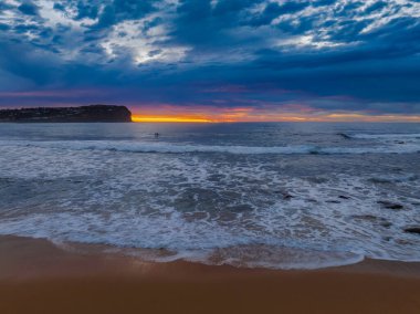 Aerial sunrise with medium and high cloud filled sky with small waves at  Macmasters Beach on the Central Coast, NSW, Australia.