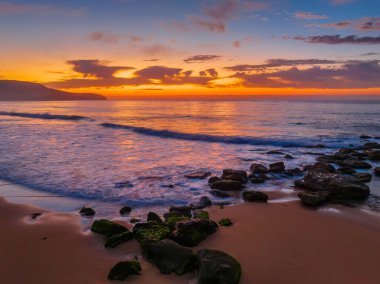 Deniz kıyısında hava gündoğumu yumuşak bulutlar ve küçük dalgalar ile Orta Sahildeki Killcare Sahili 'nde dalgalanan, NSW, Avustralya.