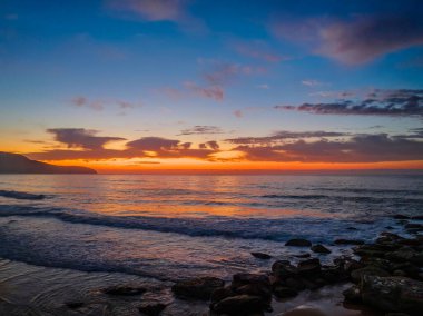 Deniz kıyısında hava gündoğumu yumuşak bulutlar ve küçük dalgalar ile Orta Sahildeki Killcare Sahili 'nde dalgalanan, NSW, Avustralya.