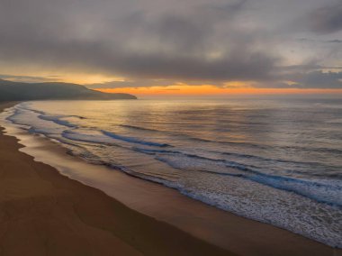 Deniz kıyısında, yumuşak bulut ve sisle birlikte hava gündoğumu Central Coast, NSW, Avustralya 'daki Killcare Plajı' nda ilerliyor..