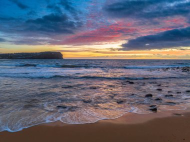 Deniz kıyısında hava gündoğumu bulutlar ve dalgalar ile Central Coast, NSW, Avustralya 'daki Macmaster Sahili' nde.