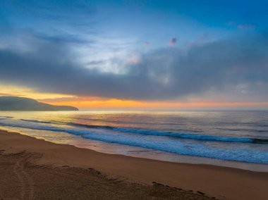 Deniz kıyısında, yumuşak bulut ve sisle birlikte hava gündoğumu Central Coast, NSW, Avustralya 'daki Killcare Plajı' nda ilerliyor..
