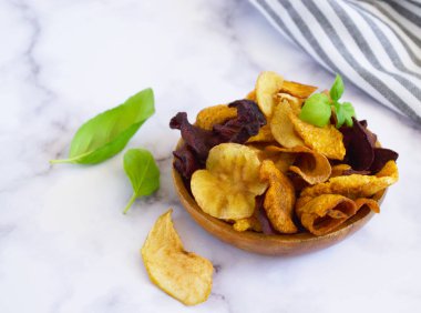 Vejetaryen atıştırmalıkları, ahşap kasede çok renkli sebze cipsleri ve taze çiftçi sebzeleri, sade yaşam, seçici odaklanma..