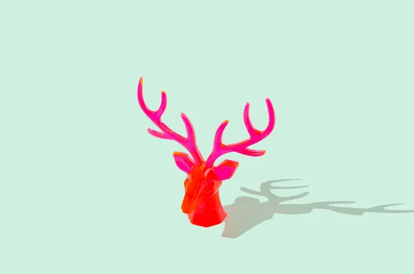 Neon kırmızı ren geyiği kafası pastel yeşil arka planda izole edilmiş. Yaratıcı Noel ve Yeni Yıl kutlaması konsepti. Kopyalama alanı olan en küçük bayrak.
