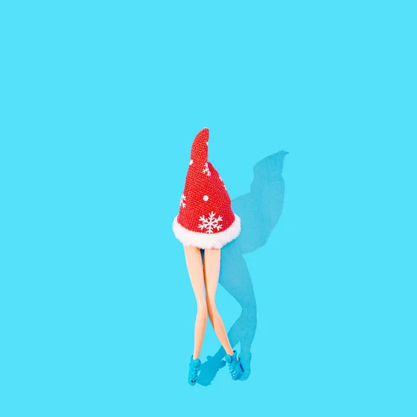 Mavi ayakkabılı ve kırmızı Noel Baba şapkalı kadın bacakları. Pastel mavi arka plan. Bayram tatili yaratıcı konsepti. Asgari Noel veya Yeni Yıl kutlamaları ruh hali sanatsal tasarımı.