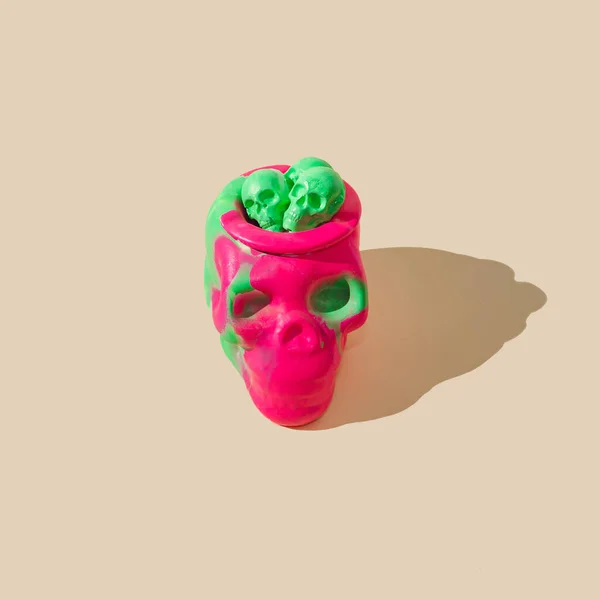 緑色の目をしたフクシアの頭蓋骨 小さな緑色の頭蓋骨が頭の上から出てきています ベージュの背景 不気味なハロウィーンパーティー招待コンセプト 流行の怖い芸術デザイン — ストック写真