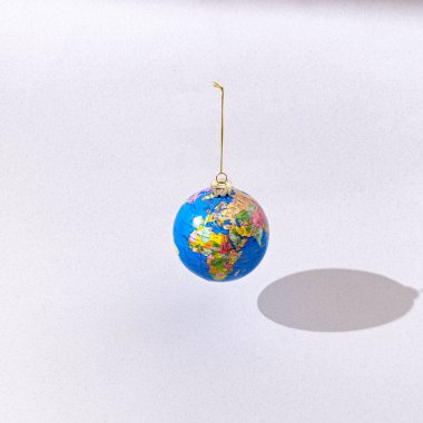 Açık gri arka planda Noel topu gibi sallanan bir küre. Gerçeküstü Noel ya da yeni yıl minimum yaratıcı konsepti. Dünya çapında Noel ya da yeni yıl partisi için afiş ya da kart.