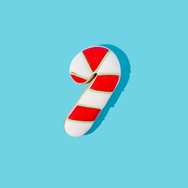 Pastel mavi arka planda zencefilli kekten yapılmış kırmızı ve beyaz bir çubuk şeker. Pankart veya pankart için asgari geleneksel Noel veya yeni yıl konsepti.