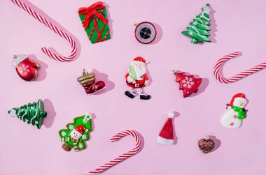 Çeşitli sembolik Noel ya da yeni yıl süsleri ya da pastel pembe arka planda kırmızı, yeşil ve beyaz süslemeler. Festival kartı, afiş ya da davetiye için desen ya da duvar kağıdı.