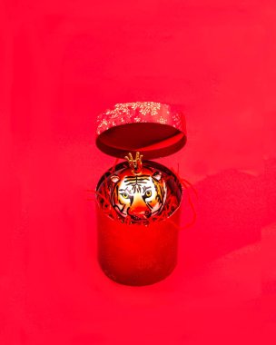 Kırmızı arka planda kırmızı bir hediye kutusundan çıkan kaplan şeklinde bir süsleme. 2022 Çin Yeni Yılı için kaplan burcunda yaratıcı bir kavram. Kart veya pankart için tasarım.