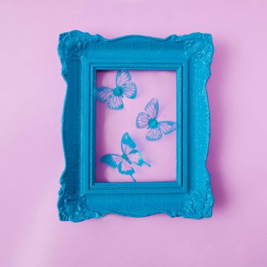 Pastel pembe arka planda mavi kelebekli eski moda pastel mavi bir çerçeve. Kart, web pankartı veya başyazı için romantik bahar tasarımı