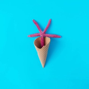 Mavi arka planda kızıl deniz yıldızı olan dondurma külahı. Yaz tatlıları ya da dondurmacılar için minimum konsept. Yaz tatilleri için afiş ya da yazı tasarımı.