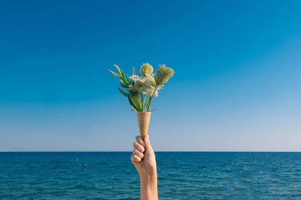 Een Meisjeshand Die Een Ijskegel Vasthoudt Met Wilde Bloemen Tegen — Stockfoto