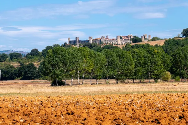 Küçük bir ortaçağ kasabası olan Monteriggioni, güneşli bir yaz gününde Francigena yolundan gökyüzüne yükselir.
