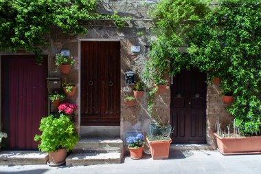 Küçük ortaçağ kasabasındaki eski binalar Pitigliano, Tuscany, duvarlarında kavanozlar ve çiçeklerle