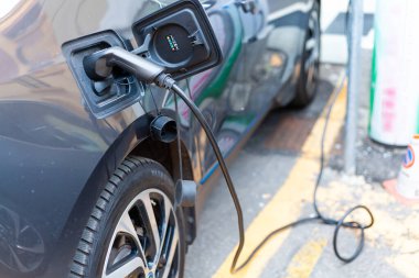Şarj istasyonundaki gri bir elektrikli arabaya bağlı bir kablo.