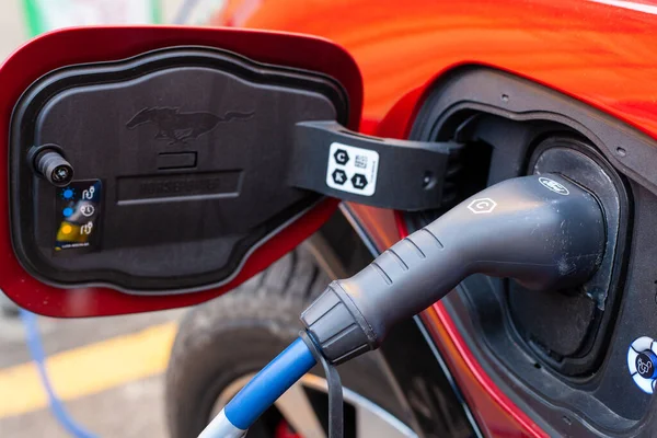 Şarj istasyonundaki kırmızı, şık bir elektrikli arabaya bağlı bir kablo.