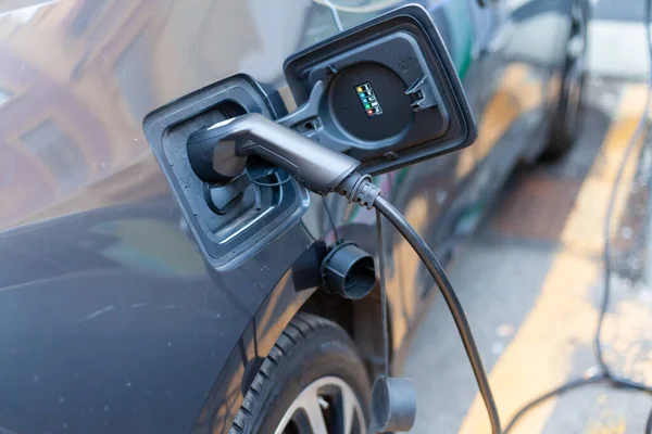 Şarj istasyonundaki gri bir elektrikli arabaya bağlı bir kablo.