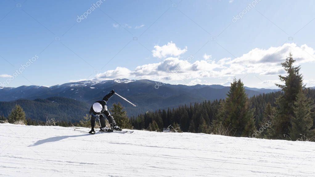 Child downhill skiing on snowy slope high in mountains fall, risking injury. Boy skier at winter resort against background mountain landscape. Winter vacation, Insurance in extreme sport. Copy space