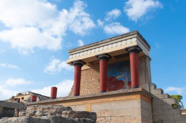 Yunanistan 'ın Girit Adası, Heraklion' daki Minos Sarayı Knossos. Yükselen boğa freski ve bulutlu gökyüzüne karşı üç kırmızı kolon ile Kuzey Girişi