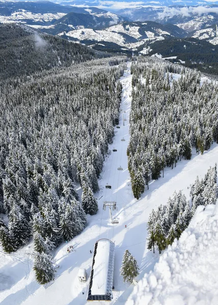 Aerial view of lift in ski resort Pamporovo, Bulgaria. Winter landscape with snow-covered fir trees, chairlift and mountain range. Christmas holidays travel destinations