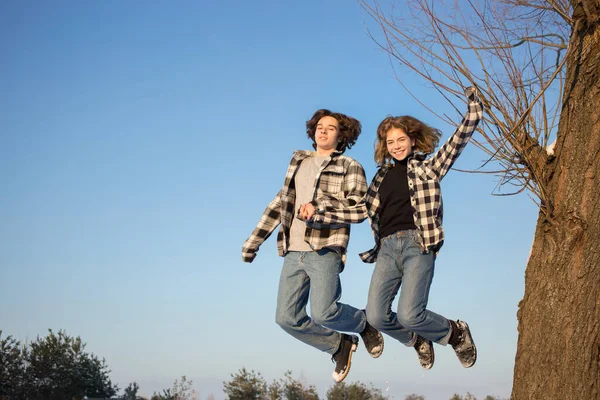 穿着格子呢衬衫和牛仔裤的快乐快乐的年轻人和女孩在外面的蓝天中跳跃着 生活方式 享受这一刻 快乐的心情 情人节 — 图库照片
