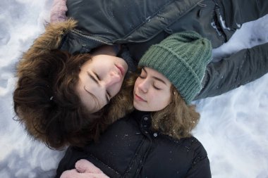 Karda, sıcak giysiler içinde yatan mutlu genç bir çiftin yüzleri. Özgürlük, dikkatsizlik, yaşam tarzı, zevk anı, aşk duyguları, ilişkiler. Sevgililer Günü. Bir kış gününde yürümek