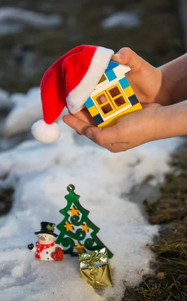 Dłonie Dzieci Trzymają Mały Dom Wykonany Zestawu Budowlanego Czapce Mikołaja — Zdjęcie stockowe