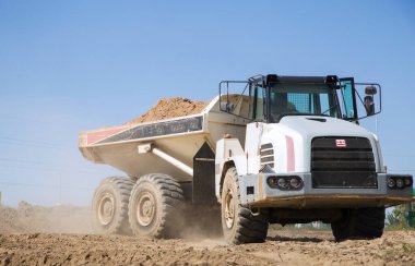 large gray articulated dumper at a construction site drives down a dusty road . loading and transportation of soil. clipart