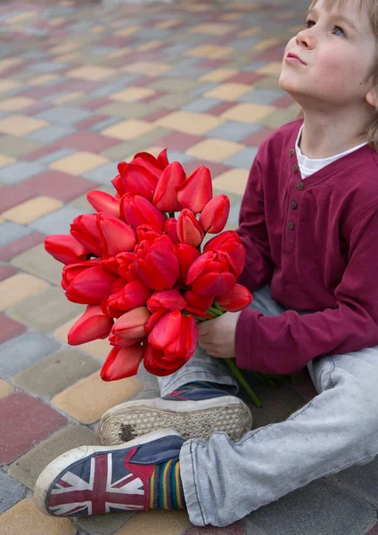 Aranyos Fiú Éves Tart Egy Nagy Csokor Vörös Tulipán Felnéz — Stock Fotó