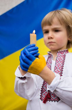 Ukrayna bayrağının renklerine boyanmış çocukların ellerinde yanan bir mum var. Çocuğun Ukrayna 'daki savaşı durdurma isteği. Ulusal bağımsızlık. Çocuklar savaşa karşı. Dua, İnanç, Umut