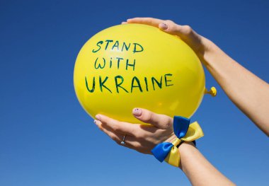 Üzerinde yazı olan sarı balon mavi gökyüzüne karşı Ukrayna ile duruyor. Ukrayna ile dayanışma. Vatanseverlik ve birlik kavramı. Rusya ile savaş