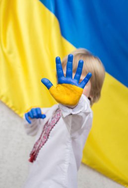 hands of an unrecognizable child painted in yellow and blue colors of Ukrainian flag. request of Ukrainians to stop the war in Ukraine. national independence. children against war