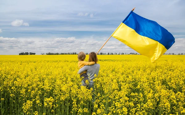 Мати Сином Руках Великим Атласним Прапором України Серед Квітучого Жовтого — стокове фото