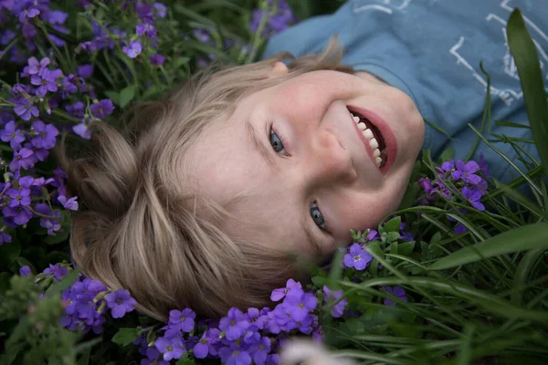 Portrait Cute Smiling Boy Lying Grass Small Purple Flowers Summer — Foto de Stock