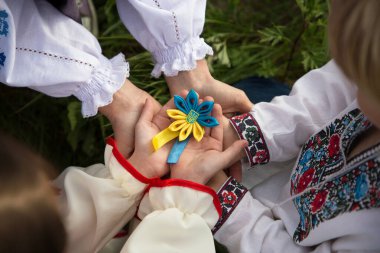 İşlemeli tişörtlerin içinde çocuklar ve yetişkinlerin elleri dikkatle birliğin içinde Ukrayna 'nın mavi-sarı mızrağını tutuyorlar. Ukrayna 'nın yanında dur. Vatanseverler, ulusal gurur. Ukrayna 'daki savaşı durdurun. Yardım çağır.